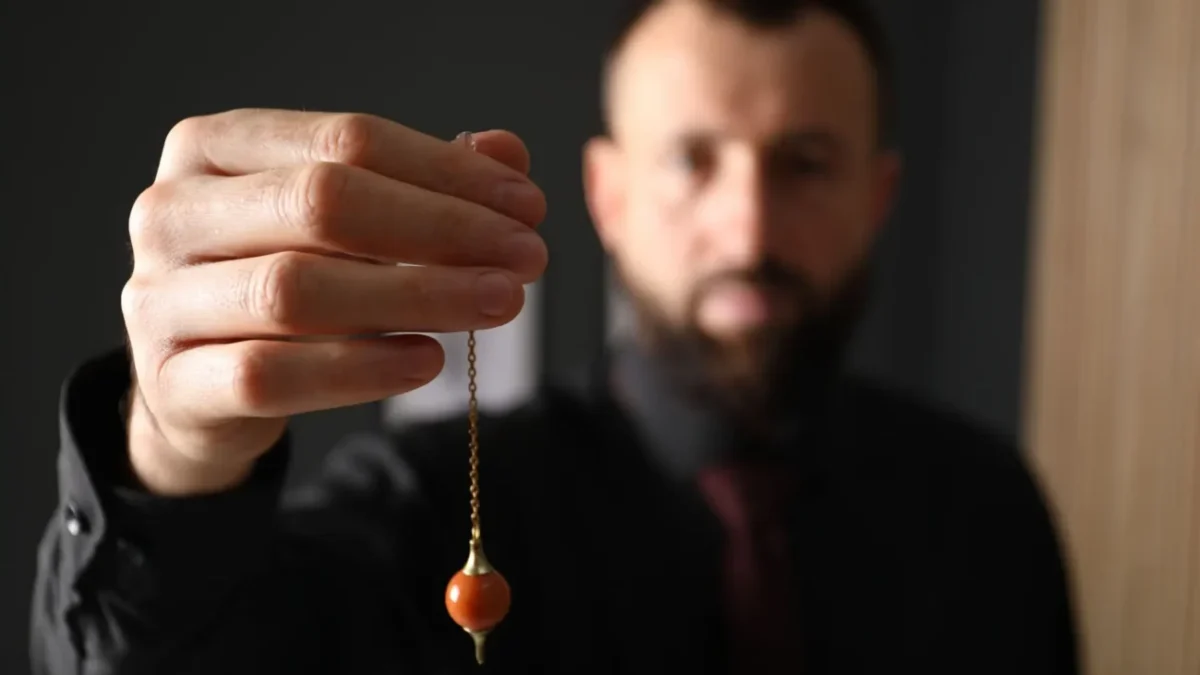 hypnotizér drží v ruce kyvadlo