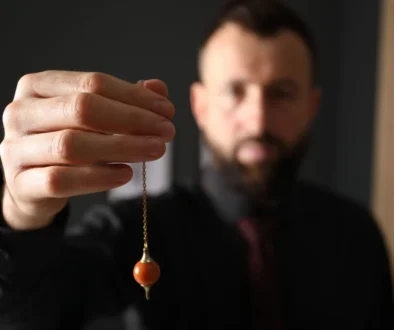 hypnotizér drží v ruce kyvadlo