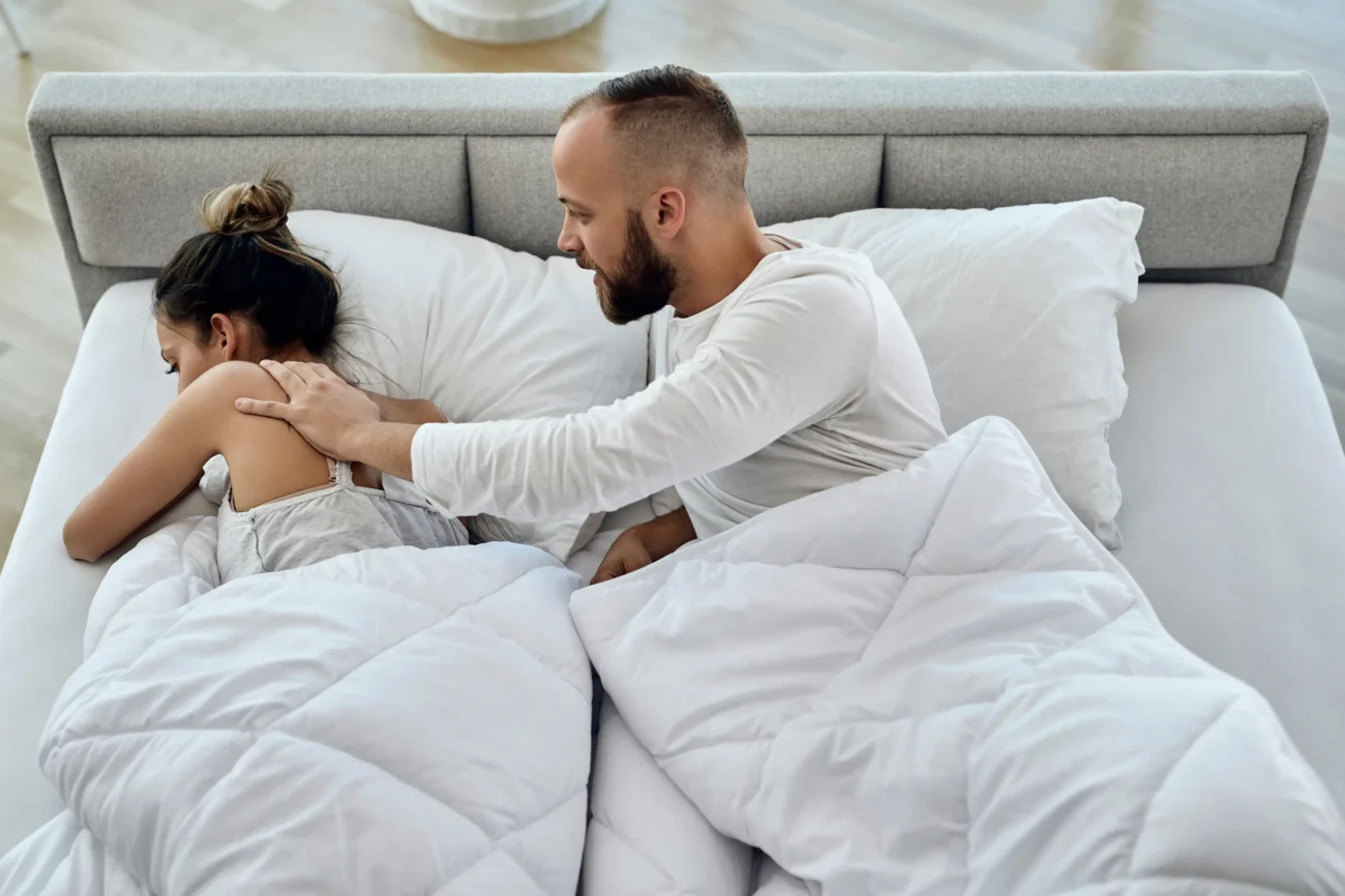 shutterstock_1747777427-2 | TVGURU.cz Muž v posteli sahá na naštvanou ženu.