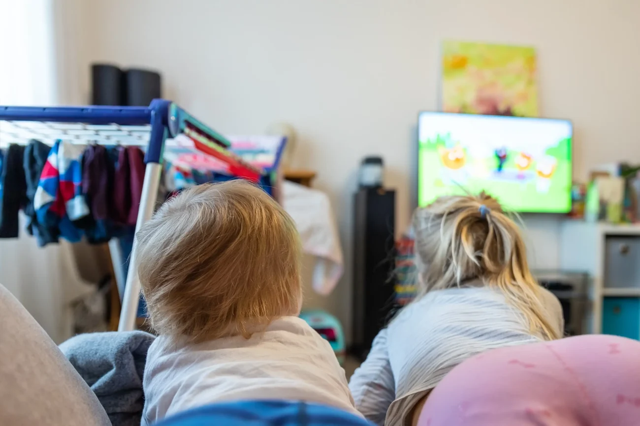 shutterstock_1689250519-2 | TVGURU.cz Děti leží na gauči a dívají se na televizi.