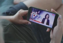 Ruce držící telefon s živým vysílláním.