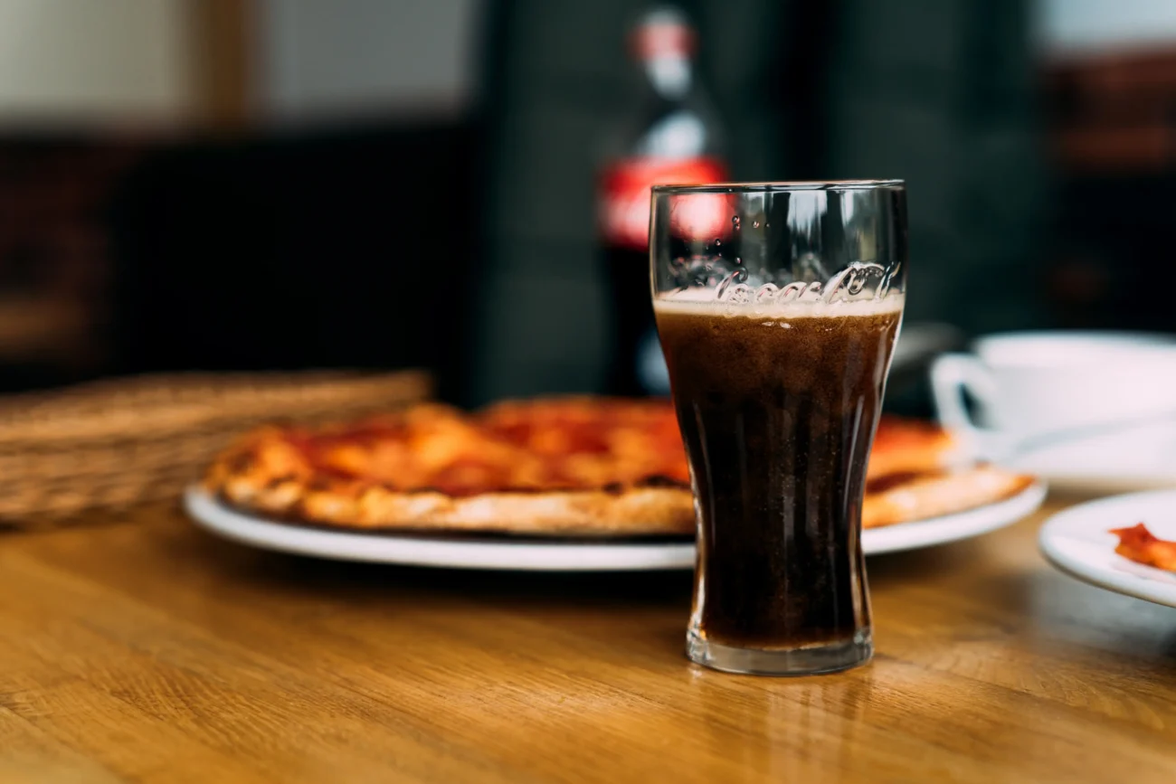 shutterstock_1627803130-2 | TVGURU.cz Před pizzou stojí sklenice Coca-Coly.