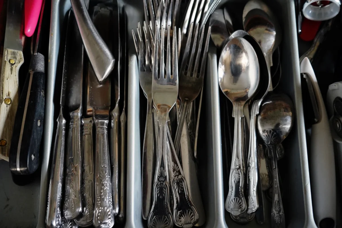Staré zdobené vidličky v příborníku mezi lžičkami a noži.