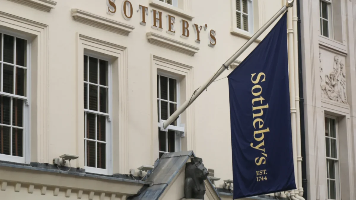 Bílé průčelí aukční síně Sotheby's s modrou vlajkou se zlatým nápisem.
