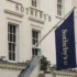 Bílé průčelí aukční síně Sotheby's s modrou vlajkou se zlatým nápisem.