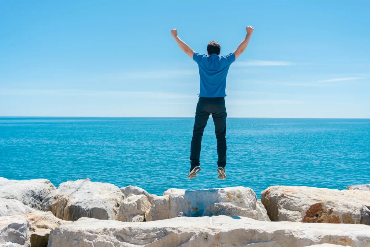 Muž skákající s rukama nad hlavou.