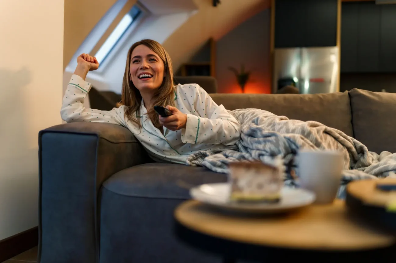 spokojená žena na gauči s ovladačem sleduje televizi