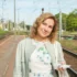 Žena stojí venku a dívá se přímo do kamery.