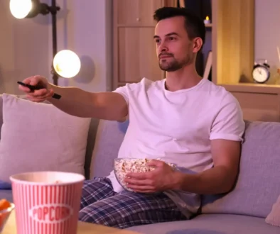 muž s popcornem z gauče sleduje televizi