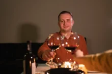 Muž si s někým připíjí.