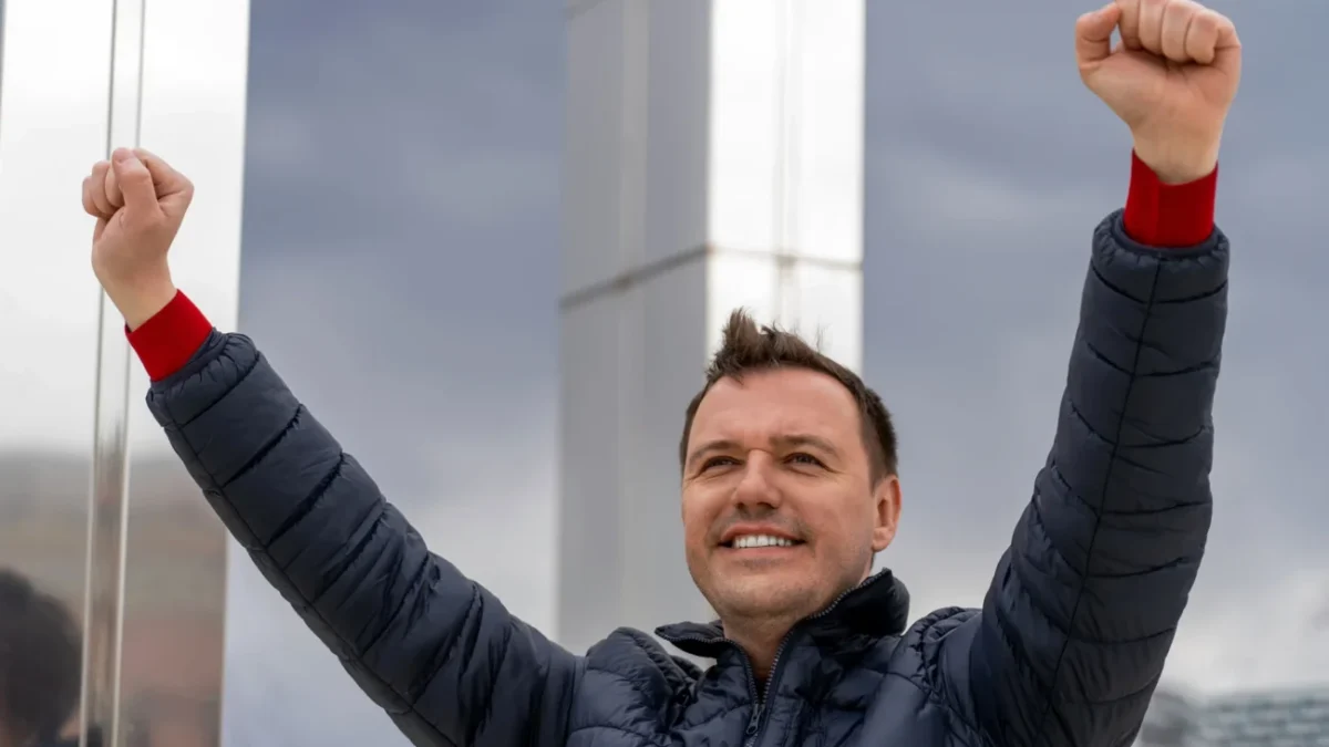 Muž zvedá ruce do vzduchu.