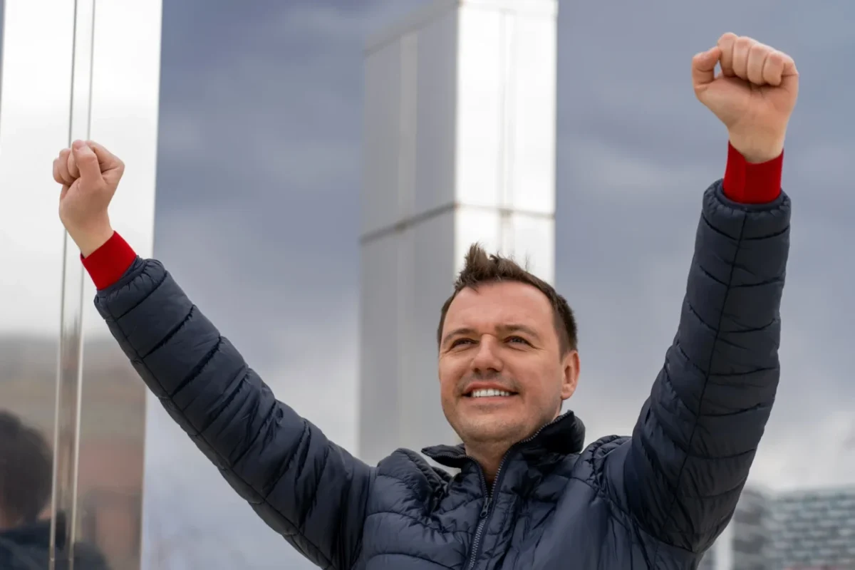 Muž zvedá ruce do vzduchu.