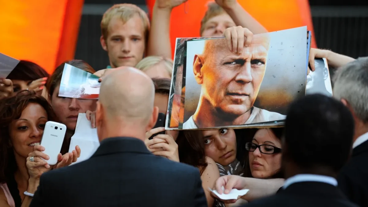 Bruce Willis obklopený fanoušky.