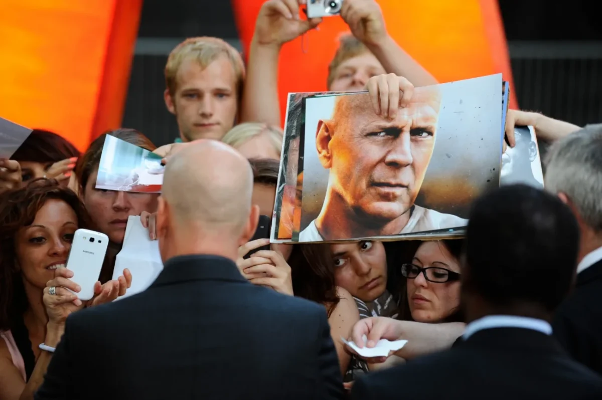 Bruce Willis obklopený fanoušky.