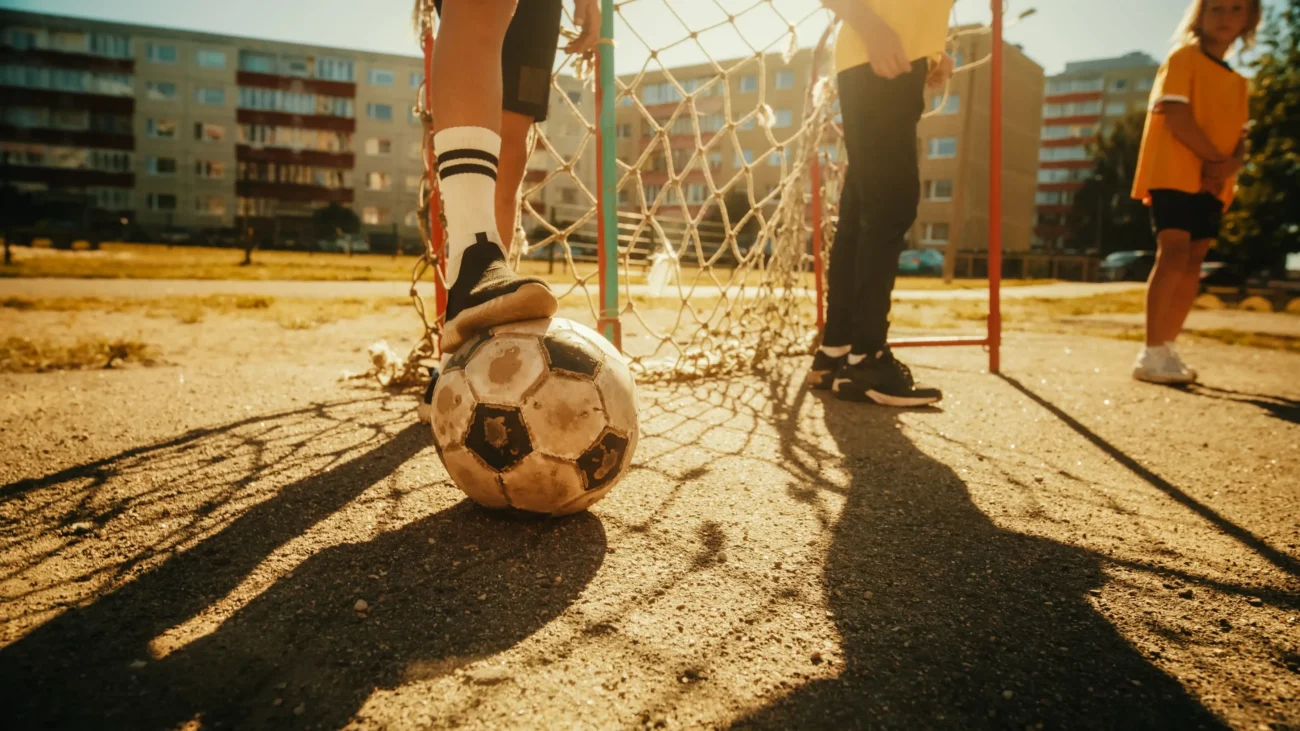 Mladí chlapci hrají fotbal na sídlišti. 