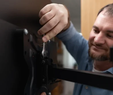 Muž se usmívá a montuje televizi.
