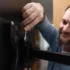 Muž se usmívá a montuje televizi.
