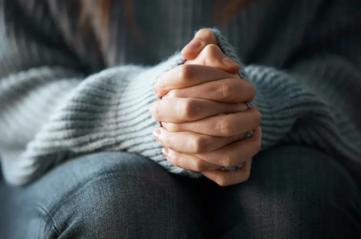 žena sedí s přeloženýma rukama v klíně