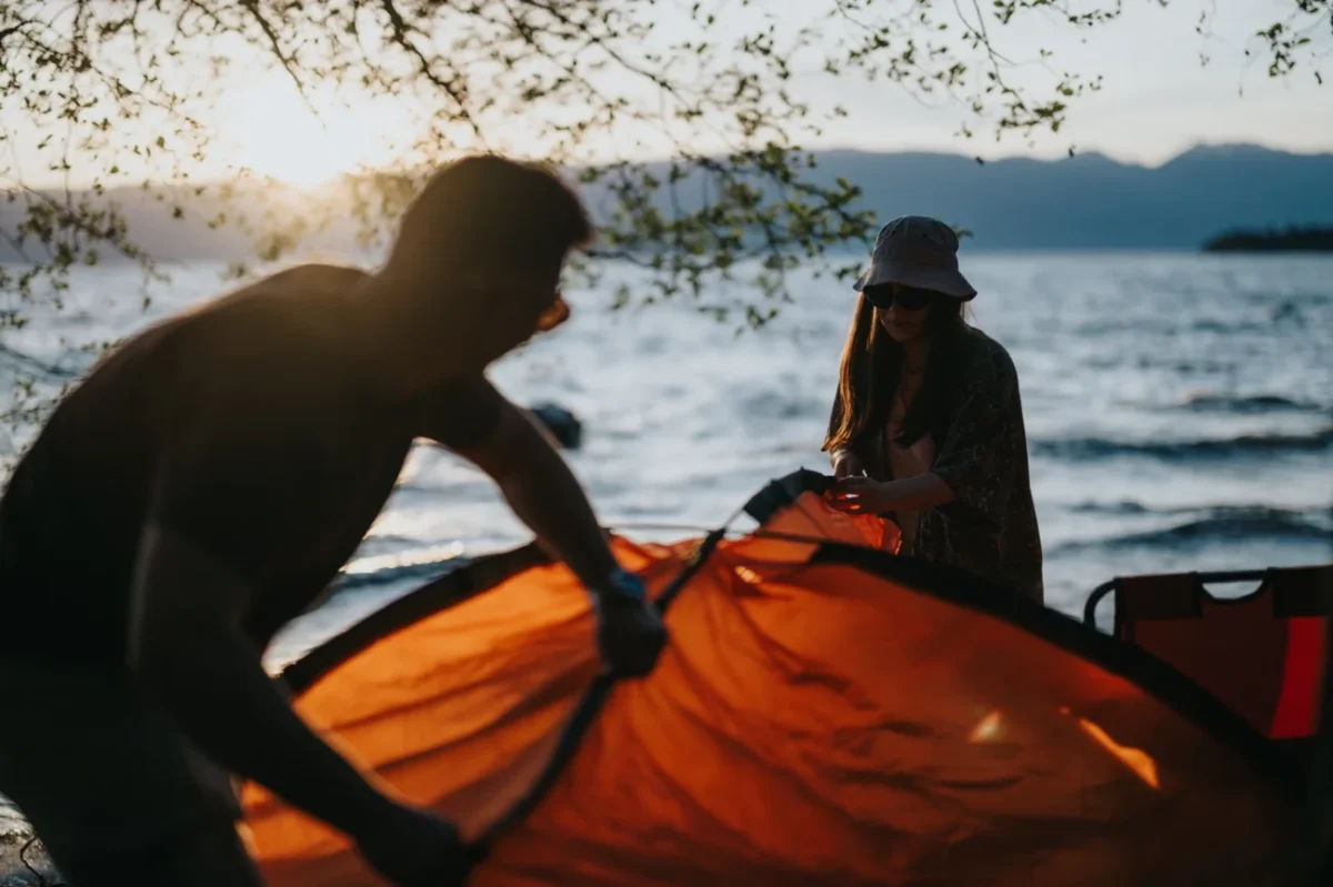 Lidé kempující u vody.