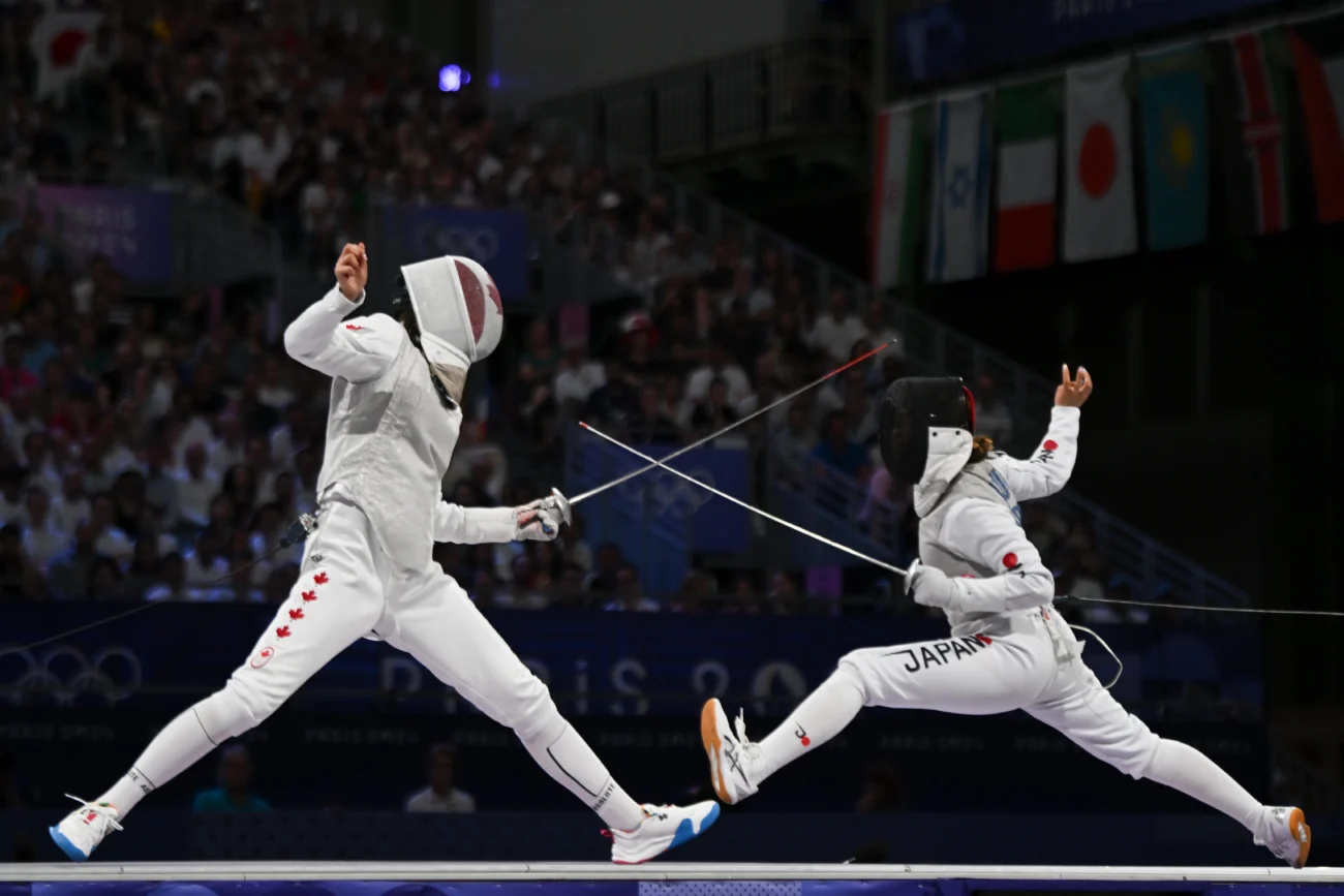 shutterstock_2591076167 | TVGURU.cz šerm - dva sportovci s meči v bílých kombinézách a s chránič - souboj před diváky v aréně na soutěži - dramatická pozice s napřaženými meči proti sobě