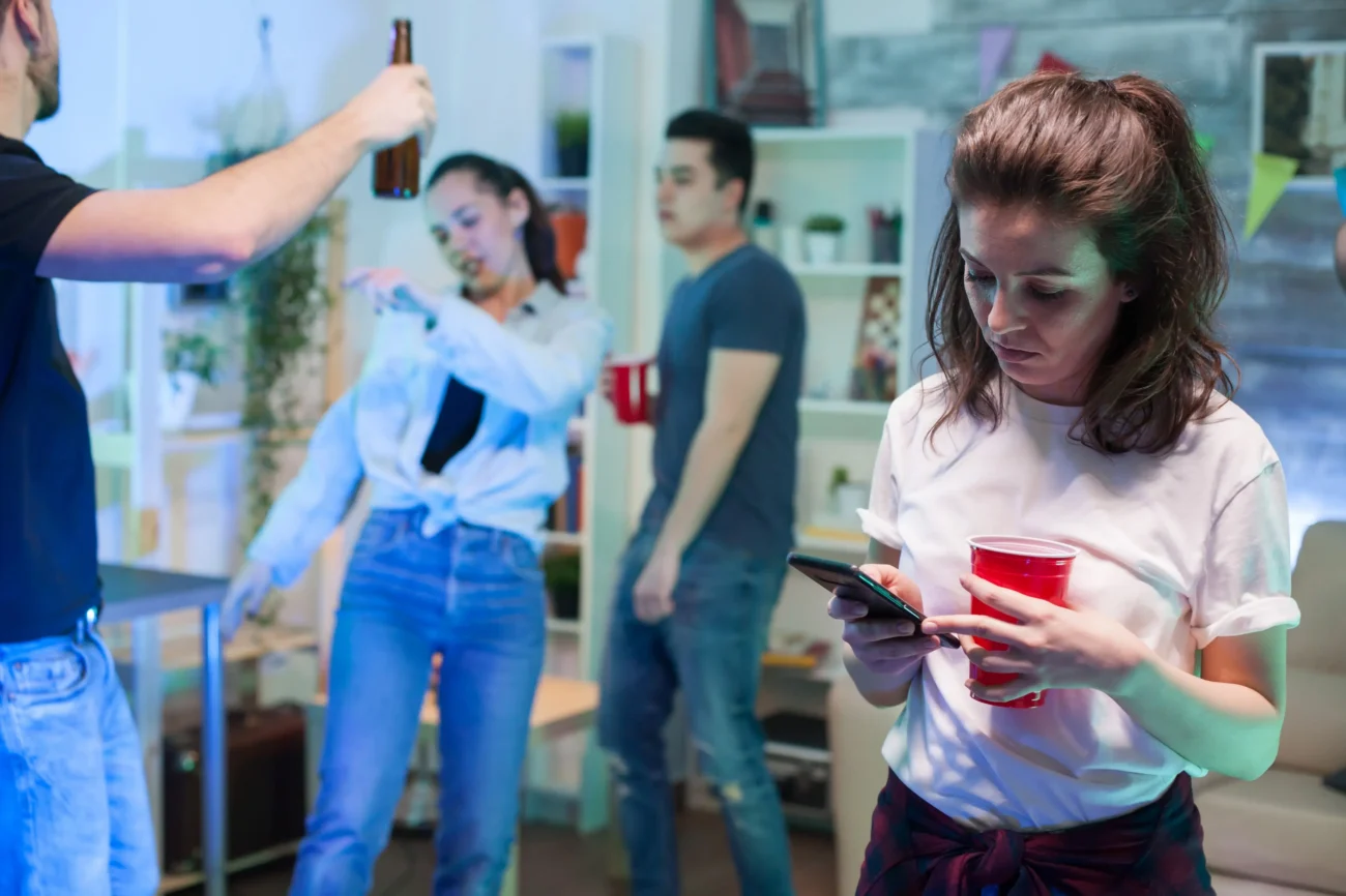 Někdo potřebuje na seznámí dostatek času. Zdroj: Shutterstock | TVGURU.cz Žena stojící dál od lidí na party.