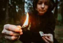 mladá dívka-žhářka drří v ruce zapálenou sirku