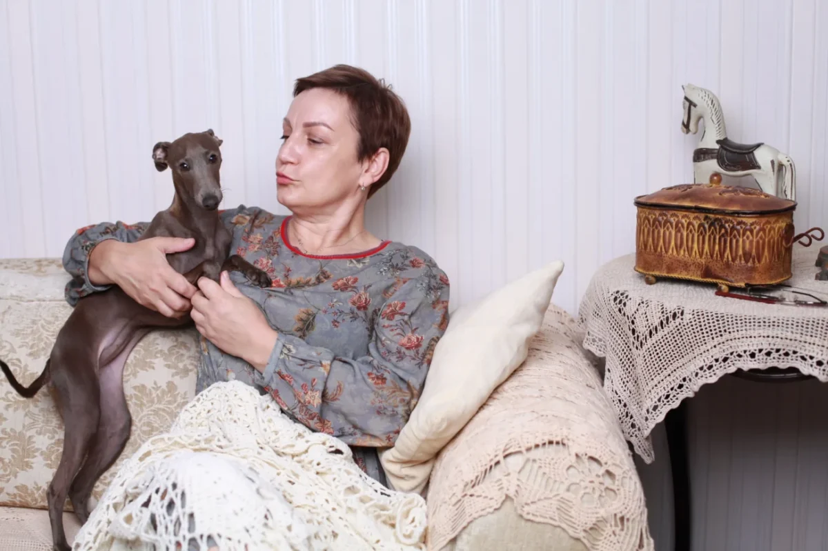 Žena s pejskem sedí na gauči.