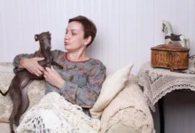Žena s pejskem sedí na gauči.