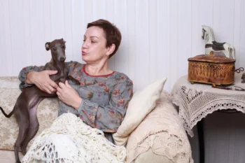 Žena s pejskem sedí na gauči.