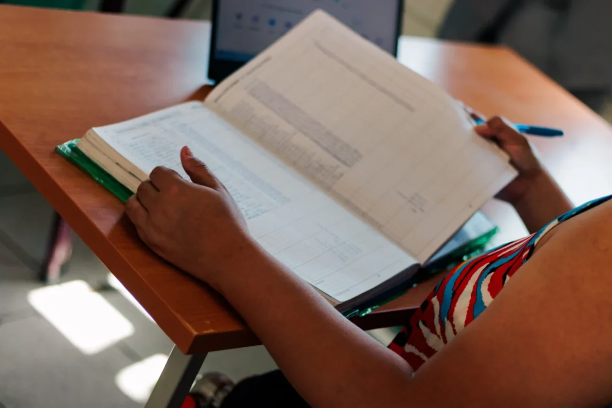 žena listuje a vyplňuje v sešitě