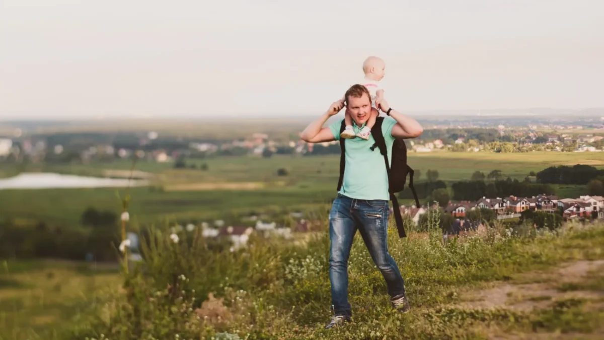 Muž s miminkem se prochází přírodou.