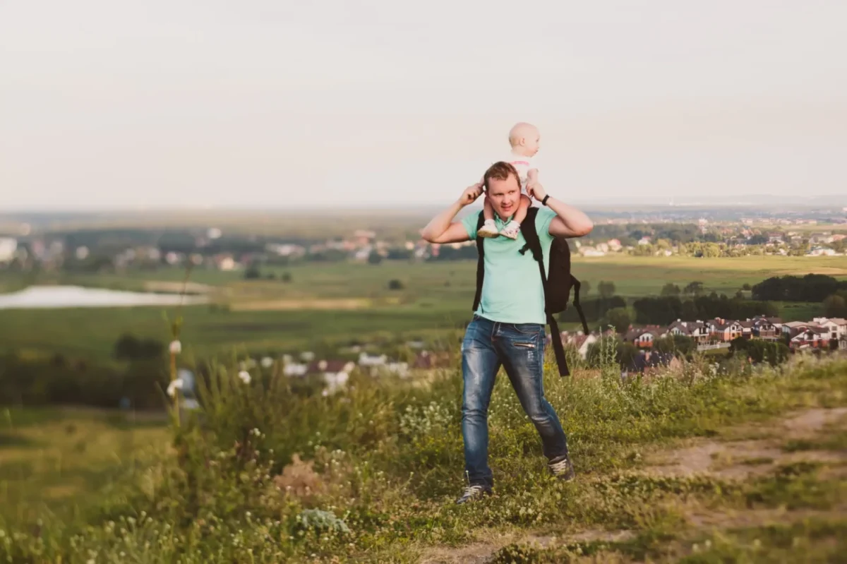 Muž s miminkem se prochází přírodou.