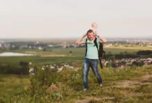 Muž s miminkem se prochází přírodou.
