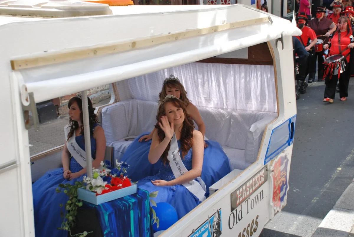 tři ženy s korunkami na hlavě mávají z lodi