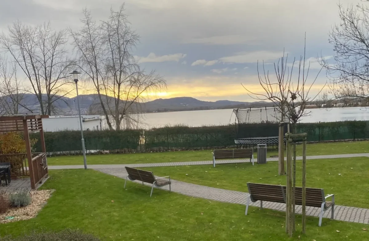 cesta a řeka s horama v pozadí, lavičky okolo