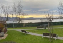 cesta a řeka s horama v pozadí, lavičky okolo