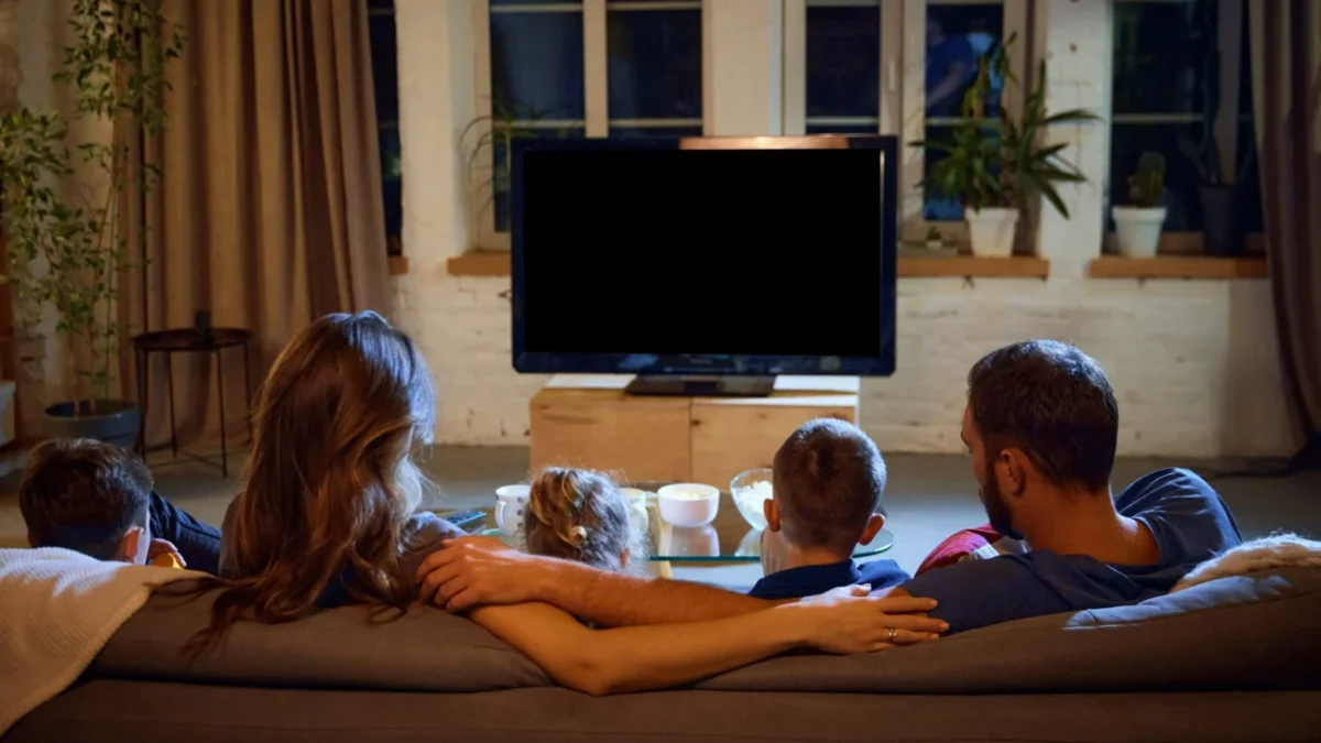 Rodina sedící na gauči u televize.