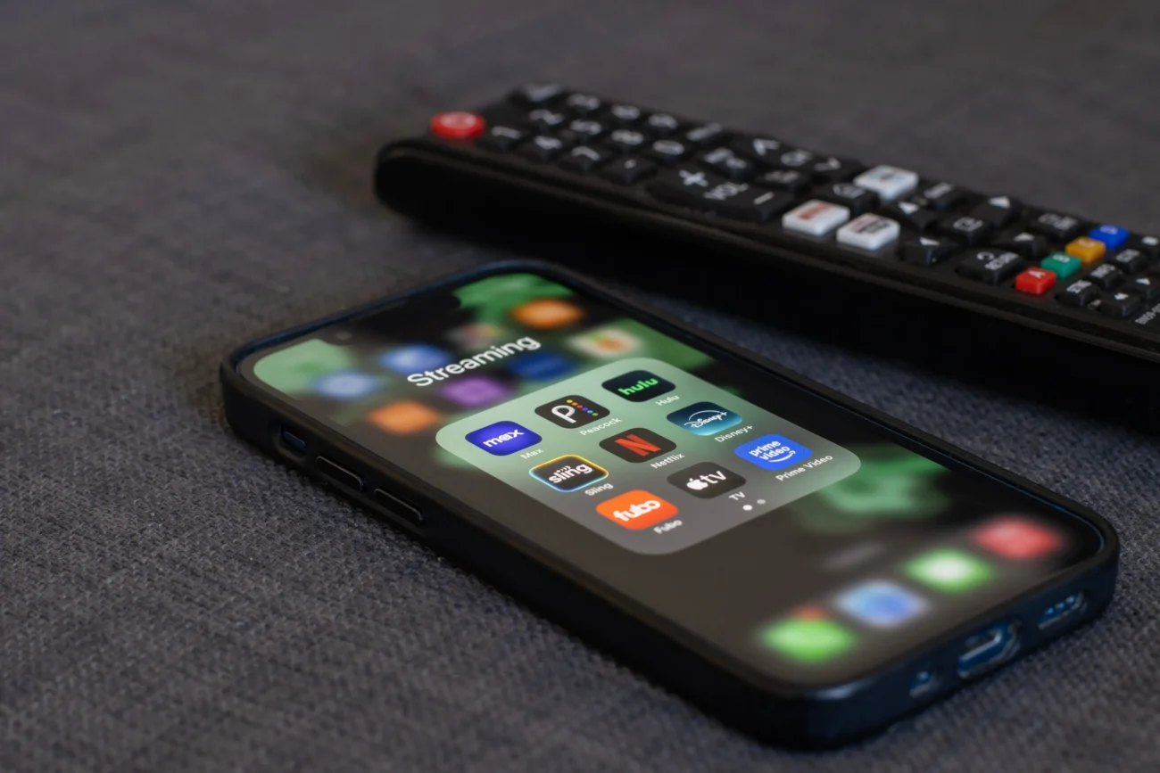 Sledovat jej lze zadarmo z různých zařízení. Zdroj: Shutterstock | TVGURU.cz Telefon a ovladač s Netflixem.
