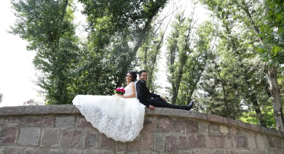 muž a žena ve svatebním sedí na mostě a fotí se na svatební fotografii