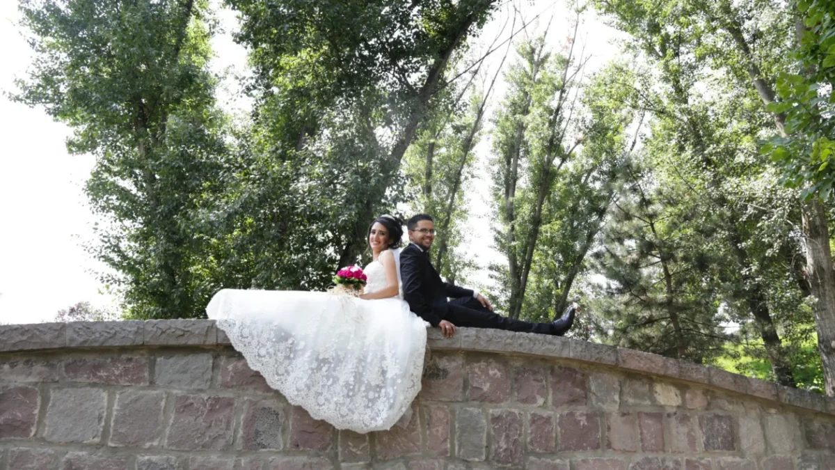 muž a žena ve svatebním sedí na mostě a fotí se na svatební fotografii