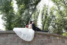 muž a žena ve svatebním sedí na mostě a fotí se na svatební fotografii