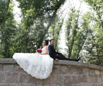 muž a žena ve svatebním sedí na mostě a fotí se na svatební fotografii