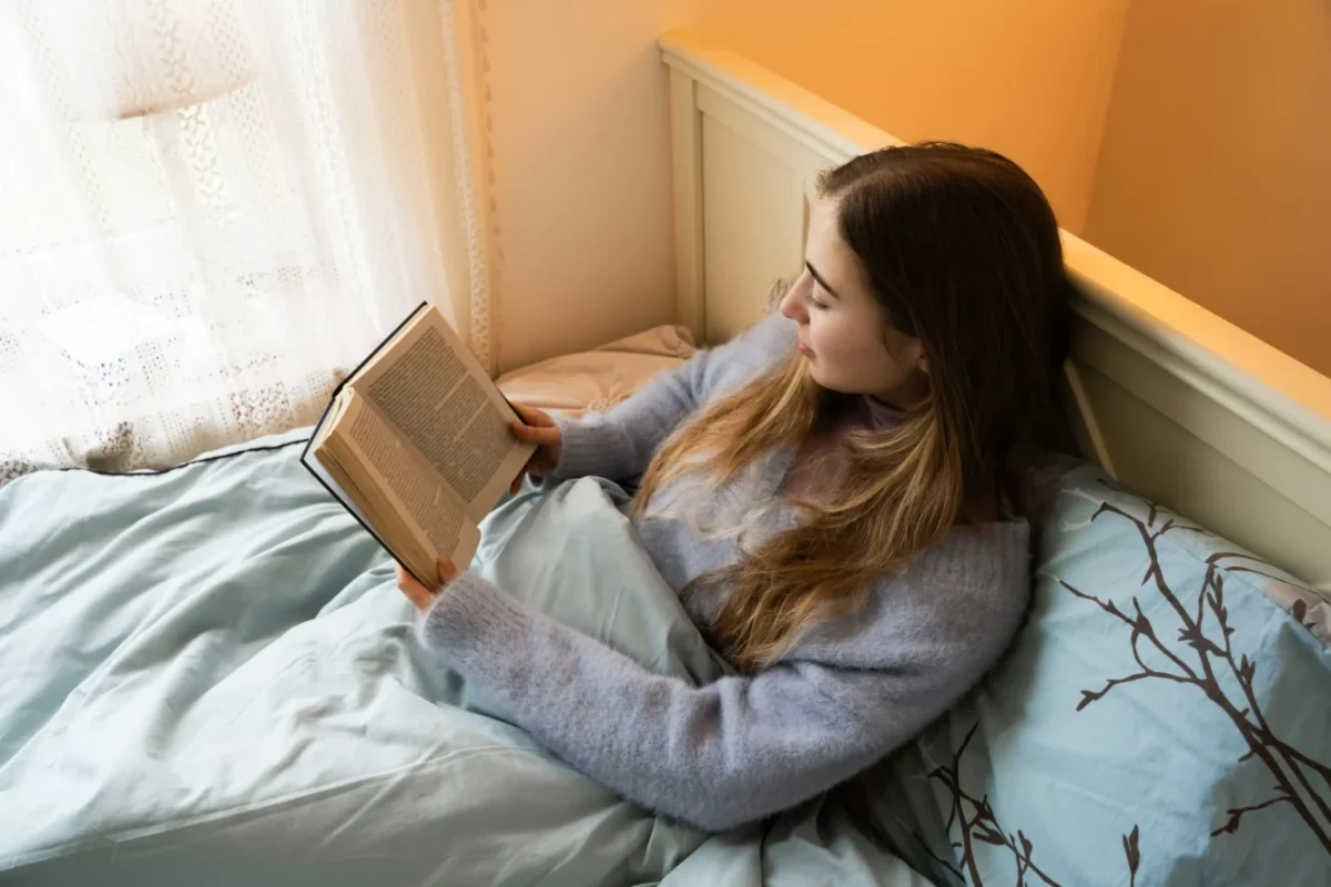Žena v posteli, která si čte knihu.
