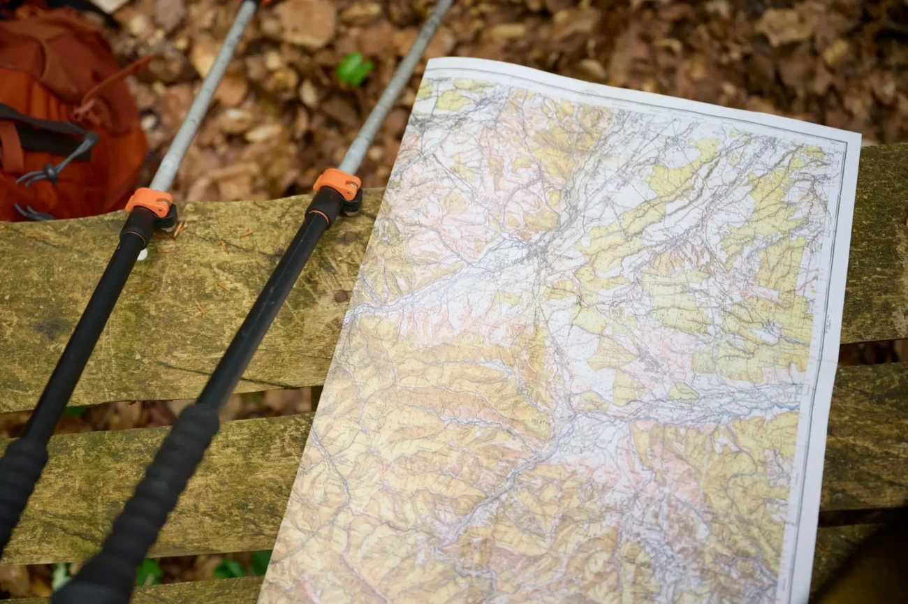 turistická mapa na lavičce , vedle ní turistické hůlky