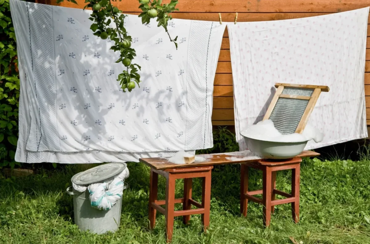retro povlečení, které se suší na zahradě, vedle něj je valcha
