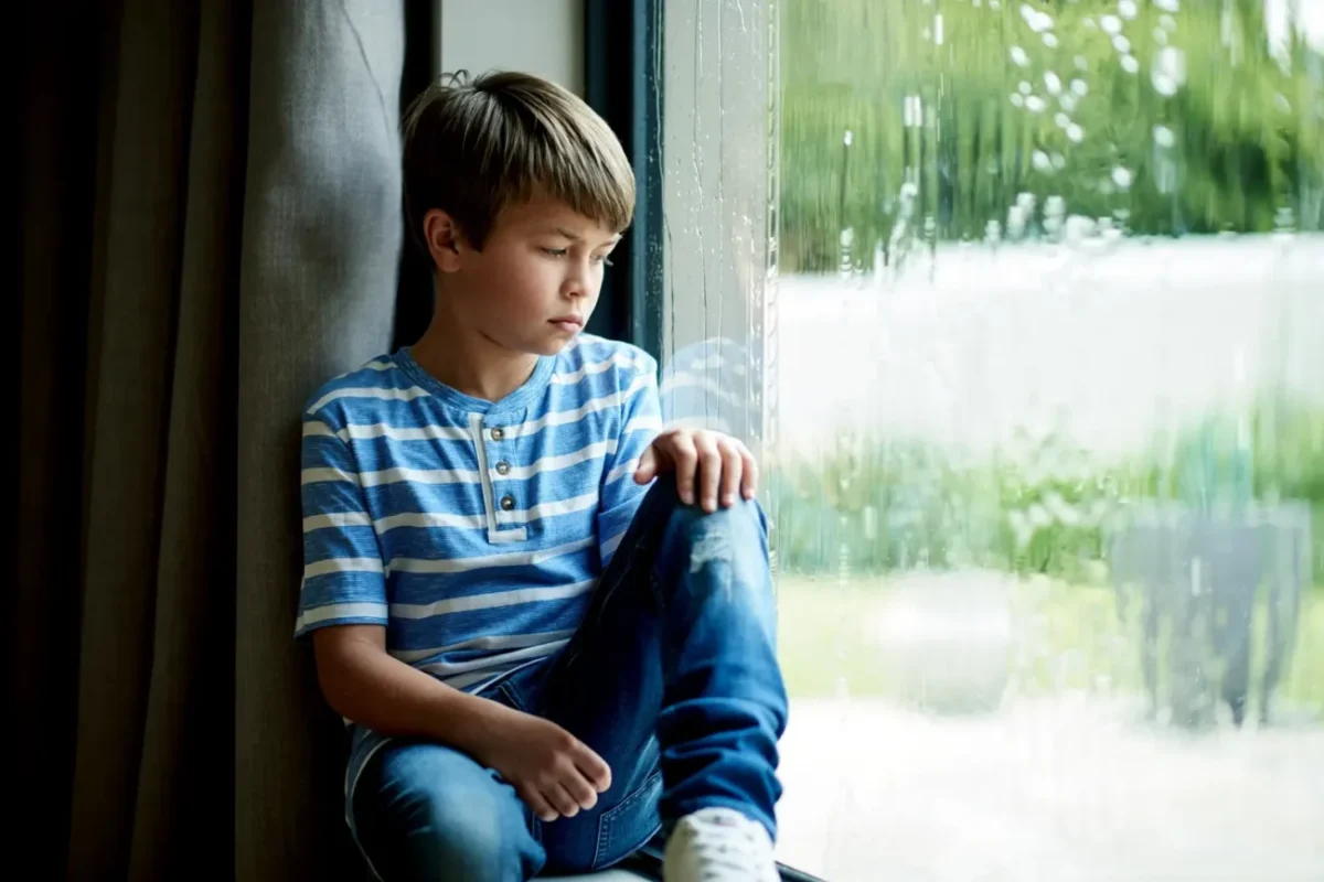 dítě sedí u okna, prší