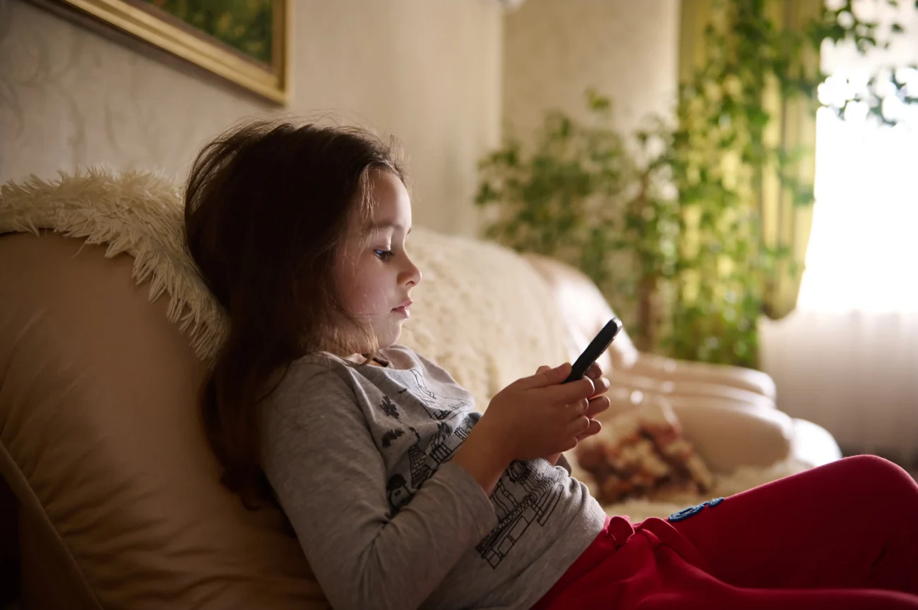 V minulosti si děti hrály s hračkami. V současné době spíše s telefonem. Zdroj: Shutterstock | TVGURU.cz Dívka hrající si na telefonu.