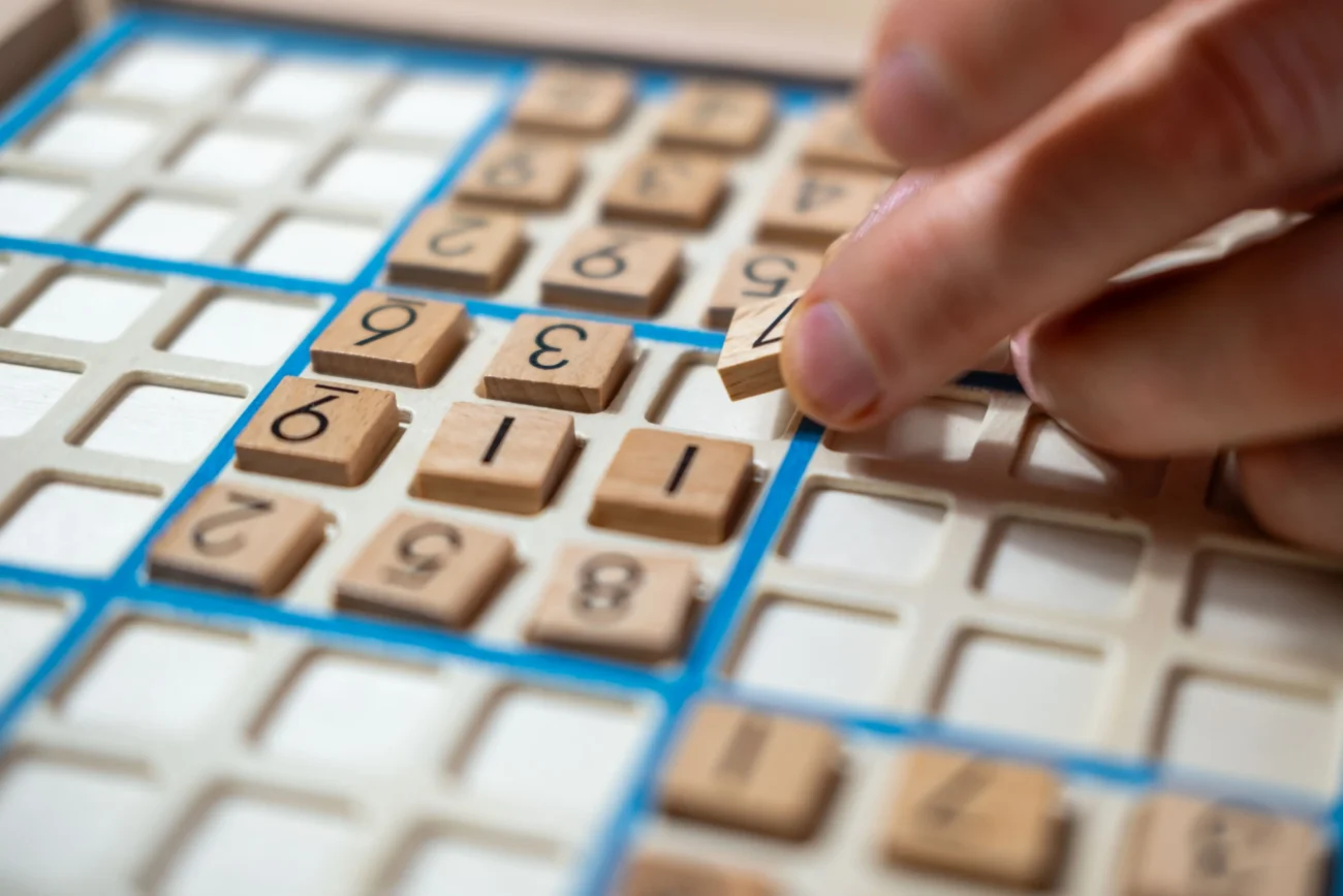 Ruka skládající dřevěné sudoku.