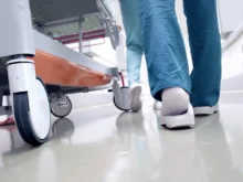 doktoři kráčí vedle pacienta, jdou vidět jen chodidla a kolečka vozíku