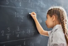 Holčička u tabule řeší matematický příklad.